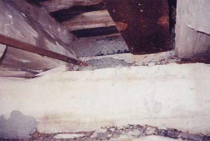 The picture shows how road traffic can track dirt into a bridge. Common accumulations include asphalt and dirt shown here encasing the abutment bearing areas and truss components. This debris can retain moisture that contributes to bridge deterioration and should be cleaned at least annually with hand tools and air-blasting as opposed to pressure washing that introduces additional water.