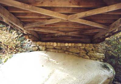 Figure 171 Brown Bridge, Shrewsbury, VT. Photo. The picture shows the underside of a bridge where the laid stone foundation rests on a natural boulder. The floor beams seem to rest on the bottom chord.