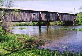 Figure 177 View of the Hamden Covered Bridge prior to work in 2000. Note the midspan timber bent added in the 1970s to help support the sagging trusses. Also note the external knee braces on either side of the temporary pier to stabilize the top chord. Photo.