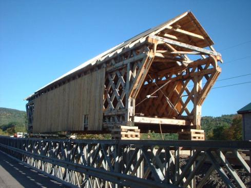 The picture shows a diagonal view of the bridge up on blocks before being lowered to its abutments. The finish work on the roof, entrances and siding is still incomplete.