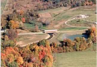 The last view is an aerial shot that shows a straight road with the new realigned bridge and riprap along the rerouted river. The river's path is more defined than the before picture with a straighter road crossing over the river.