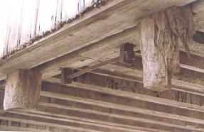 This picture of the original underside of the bridge shows the bar and rod connections used as a tensile connection that were duplicated in the rebuilt bridge. Large steel bars were inserted into the bottom chord on either side of the splice, with their ends projecting.. These bars were connected by a square steel rod with threaded ends and nuts for tightening the joint.