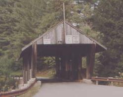 The picture shows the queenpost truss from the approach roadway. The structure appears in poor repair and is not well-aligned.