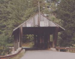 The picture shows the queenpost truss from the approach roadway. The structure appears in poor repair and is not well-aligned.