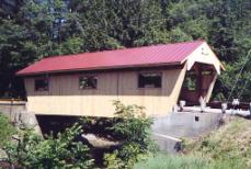 The picture shows a longitudinal view of the completed bridge, featuring concrete abutments, a metal roof, three windows, and a portal extension.