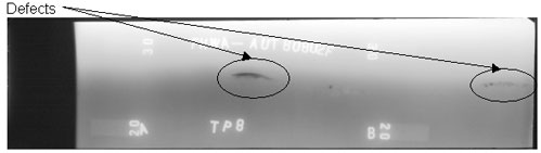 The radiographic image shows two longitudinal defects. One discontinuity is located between markers A and B while the other discontinuity is located between markers B and C (C not shown). The discontinuities are circled for illustrative purposes.