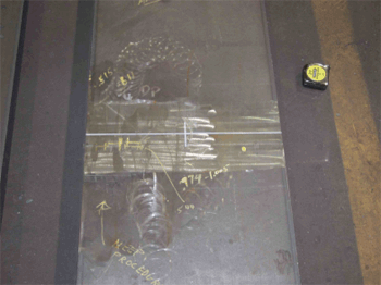 The photo shows a plan view of field specimen FG1A-TF2-BottF-FCM with the weld oriented horizontally. The specimen is comprised of plates of equal thickness and width.