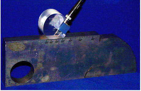 Figure 21. Photo. Sound-path angle check: Photograph shows that the selected angle transducer is positioned on the IIW type I reference block over the line indicative of the transducer angle. 