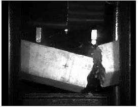 Figure 51. Photo. Two of eight plain concrete specimens initially failed with one major crack in the impact regime. This is a snapshot from a video of a test showing the damage in the loading regime of one beam. The damage is one major crack beneath one impactor.