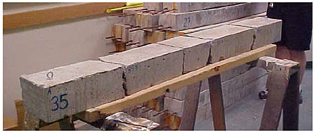 Figure 53. Photo. Four of the eight plain concrete specimens ultimately break into five pieces. This is a post-test photo of a plain concrete beam. The beam is broken into five pieces. The pieces have been removed from the test fixture and are sitting on a saw horse.