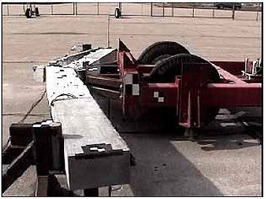 Figure 71. Photo. The beam tested at an impact velocity of 15.9 kilometers per hour (9.9 miles per hour) exhibits inclined shear cracks, localized crushing, and bond failure. One snapshot from the video of the test is shown looking at the beam from the side. It shows that damage is not symmetrical about the loading points, and congregates in one side of the beam. The beam is fractured through the thickness beneath one impactor point, then debonding occurs on that side all along the reinforcement.