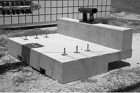 Figure 86. Photo. Parapet before test P5. This pre-test photo shows the honeycomb nose of the pendulum, just before impact with the bridge rail. Also shown is the traffic side of the bridge rail, which is attached by bolts to the reinforced concrete parapet and deck. The deck is attached to the ground with six large bolts.