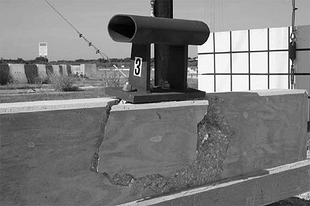 Figure 87. Photo. Parapet damage after test P3. This post-test photo shows the damage experienced by the back of the parapet in test P3. Some concrete appears to have spalled off. Large fractures extend from beneath the rail on the top of the parapet, to the back of the parapet.