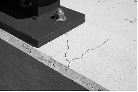 Figure 91. Photo. Parapet damage after test P7</strong>. This is a post-test view of the the top of the parapet. Two hairline cracks are evident. One extends from the bolt in the plate to the front of the parapet. The other extends from front to nearly the back of the parapet.