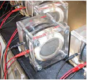 (a) shows a 102-millimeter diameter U H P C cylinder that has been cut to length and prepared for the A S T M C1202 test. (b) shows the cylinder in the testing device.