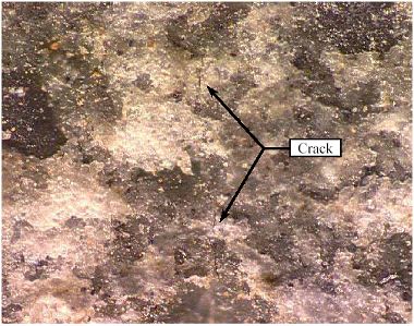 Crack in a split-cylinder tensile specimen under 350x magnification. This photo shows a crack in a split-cylinder test specimen after unloading and 350 times magnification. The crack is barely visible running vertical in the photograph.