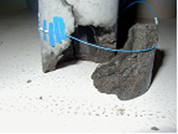 Figure 118. Photo. Water-filled, mortar-confined vial. The picture is of a broken, cracked cylinder with attached thermocouples.
