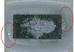 Figure 145. Photo. Second specimen, also after 4.5-hour cold soak in walk-in freezer, shows wet spots as indicated in the circled areas. The picture shows circled areas on both ends of the specimen.