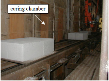 Figure 29. Photo. Units prior to entering curing chamber. Picture has an arrow pointing to the curing chamber.