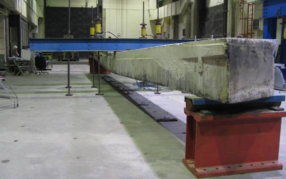 Figure 15. Photo. Deflection of Beam 4 at maximum applied load. This photo shows a view down the length of the beam when it is under approximately 458 kilonewtons (103 kips) of applied load. The beam is deflecting approximately 280 millimeters (11 inches) at midspan.