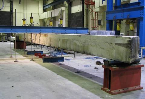Figure 3. Photo. Flexural loading of a box beam. This photo shows the test setup used for the flexural testing of individual box beams within the Turner-Fairbank Highway Research Center Structural Testing Laboratory. The beam is supported by roller bearings located at each end. Loads are applied via hydraulic jacks to two points on the beam, each being 0.91 meter (3 feet) from midspan.