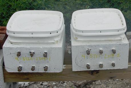 Figure 10. Photo. Two SDS specimens under exposure. This is a photograph of two SDS specimens with ponding baths under exposure.
