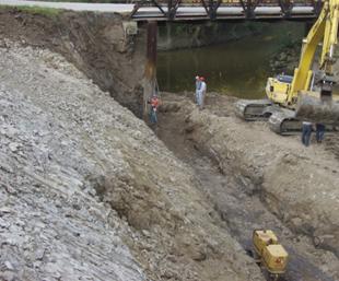 Photo showing the cut preparation of the reinforced soil foundation (RSF). The base of the excavation is being compacted before construction of the RSF with a 30-inch sheepsfoot roller compactor.