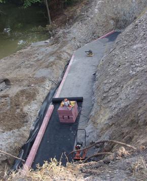 Photo showing the method of cutting a predetermined length from a roll of reinforcement and rolling it out parallel to the face of wall. This method should only be used where the reinforcement can extend all the way back to the cut-slope or in situations where secondary reinforcement layers are needed.