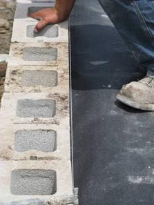 The photo shows the alignment of the facing concrete masonry unit (CMU) block with a string line referenced off the back of the block.