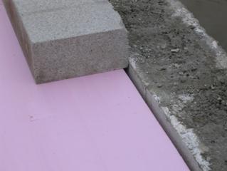 The photo is a close-up of the 4-inch foam beneath the solid 4-inch concrete block. The 4-inch concrete block is set 0.25 inch beneath the height of the facing block to prevent it from shoving forward during the compaction process.