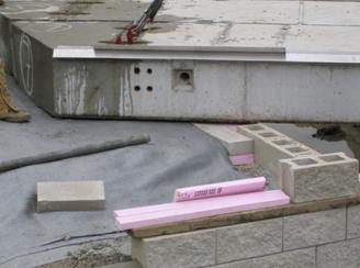 The photo shows how the top 4-inch wrapped layer of the beam seat is compacted directly against the 4-inch thick solid concrete. The photo also shows skewed concrete beams placed on the completed beam seat.