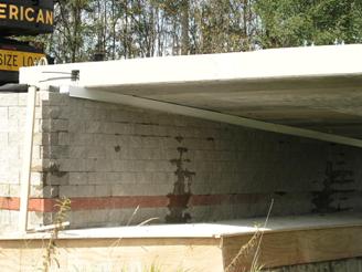 The photo shows the aluminum flashing (drip edge) located in the clear space between the beams and top row of concrete masonry unit (CMU) facing block. 