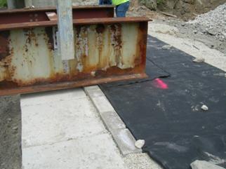 The photo shows steel beams placed directly on a geosynthetic reinforced soil (GRS) abutment for a temporary bridge. An extra sheet of geotextile was placed between the steel beams and beam seat to prevent the edges of the beams from cutting into the beam seat.