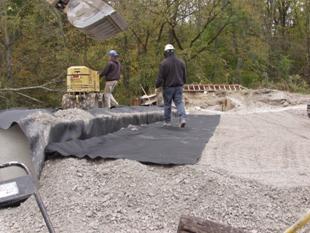 Figure 76 through figure 80 illustrate the process of forming the integrated approach by compacting layers of gravel directly against the ends of the beams. Each layer is wrapped with a sheet of geotextile. The propose of the wrapped layers is to prevent the migration of fill during thermal movement of the beams. The thickness of the each wrapped layer is about 12 inches. The 12-inch layer is compacted in 6-inch layers with small secondary sheets of reinforcement placed between each 6-inch layer at the beam ends.