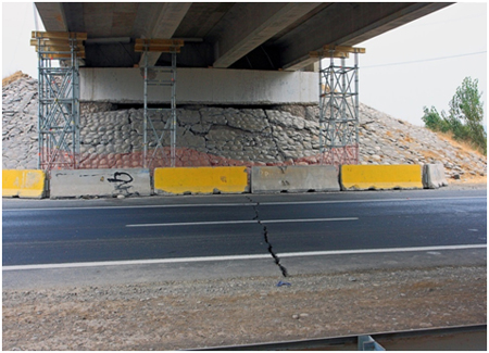 Photo. East abutment of Chada structure showing large pavement crack directly below bridge centerline. Click here for more information.