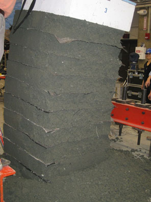 Figure 28. Photo. Tilting of the footing during TF-4 testing. Pier failure in test TF-4 results in slumping of the compacted aggregate and geotextile reinforced layers, and loose aggregate is strewn on the floor of the test facility.