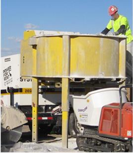 This photo shows a portable pan mixer this is being used to mix ultra-high performance concrete (UHPC) at a bridge construction site in Iowa. The mixer sits high enough above the ground to allow for discharge of fresh UHPC into a waiting motorized buggy.