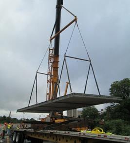 This photo shows the lifting of a precast concrete deck panel from a truck in preparation for installation on the bridge.