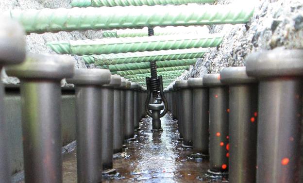 This photo shows the deck-level connection between two adjacent precast concrete deck panels along with the composite connection to the supporting girder line. The photo is a longitudinal view along the bridge at the level of the composite connection. The lap-spliced reinforcing bars and the steel shear studs are visible.