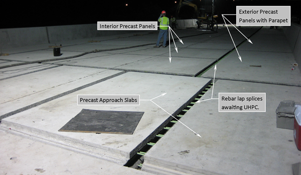 This photo shows a bridge re-decking project after installation of the full-depth precast concrete deck panels and before the casting of ultra-high performance concrete connections. Approach slabs and precast deck panels are visible.