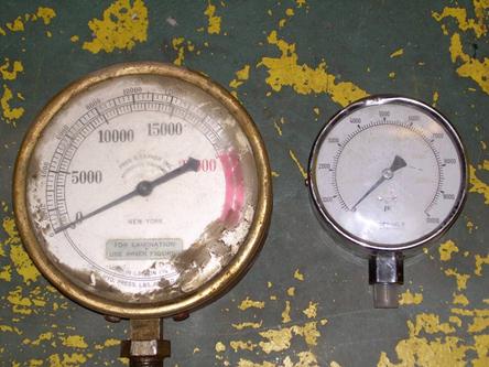 This figure shows one large and one small standard rotary dial pressure gauge. The large pressure gauge measures hydraulic pressure ranging from 0 to 20,000 lb (0 to 9,080 kg) and load ranging from 0 to 16,000 lb (0 to 7,264 kg). The small pressure gauge measures pressure from 0 to 10,000 psi (0 to 68,900 kPa).