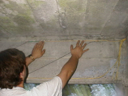 This photo shows a person applying fiber optic sensors (FOSs) to the concrete surface of a bridge prior to fiber-reinforced polymer repair.