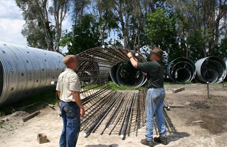 This photo shows a voided shaft reinforcement cage. The reinforcement cage used for the demonstration voided shaft is nominally 8 ft (2.44 m) in diameter, which provides 6 inches (152.4 mm) of clear concrete cover. The cage had 36 longitudinal bars with access tubes installed between every fourth bar. Clear spacing between bars and access tubes provide adequate concrete flow during concreting.