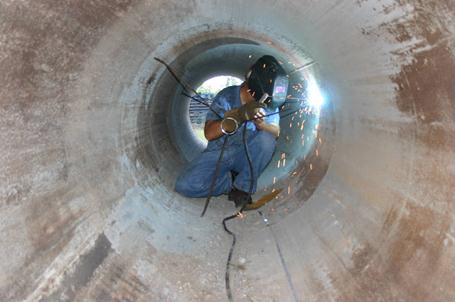 This photo shows the installation of center tube supports into the voided shaft center casing. The casing used to provide the void at the shaft center was equipped with centralizing struts welded to the inside of the casing. The struts were welded at several locations along the length of the casing and provided support for a single access tube at the shaft center.