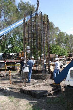 This photo shows the placement of the reinforcement cage into the voided shaft. The was held as close to center as possible prior to lowering. Wheel spacers were installed to aid in centering and providing the correct concrete cover.