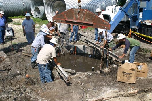 This photo shows the self-weight of the cage supported by chains, which helped maintain the correct cage elevation and prevented the bottom of the cage from resting on the soil, thereby providing the minimum steel cover at the toe of the shaft. Beams capable of support the cage self-weight were placed across the top of the surface casing to assure the chains were vertical.