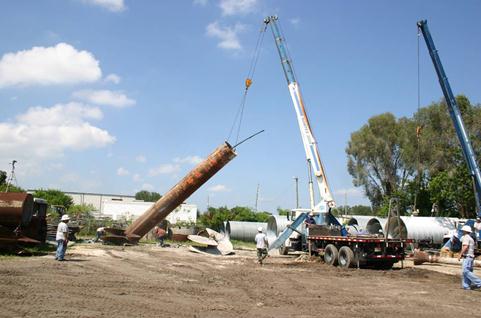 This photo shows central casing with the centralized access tube being lifted from two opposing holes in the casing near the top. Because the casing was much stiffer than the cage, it was lifted with only one boom truck.