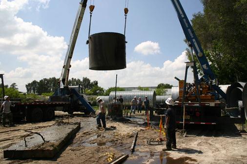 This photo shows two boom trucks lifting the outer steel casing from the voided shaft. To provide minimal disturbance to the freshly poured shaft, the trucks were used to extract the temporary surface casing. The trucks provided a more concentric removal that was minimally affected by boom deflection during loading.