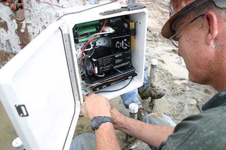 The figure shows an entire system, which contains the basic components. The null modem cable (white) is shown connected to the CR1000 (top). The cellular modem (gold) is shown on the right, while the multiplexer is near the bottom of the enclosure. Thermocouple (TC) wires were fed through the bottom of the enclosure and directly to the multiplexer. A putty-type sealant was used to keep out moisture. A desicant pack was also enclosed to absorb trapped moisture once the enclosure was closed.