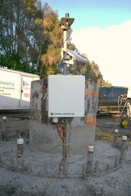 This photo shows a remote monitoring system enclosure for the voided shaft mounted to a pole, along with a wide band cellular antenna (top) and a solar panel trained on the predominant direction of the sun for that location. Thermocouple wiring can be seen running into the bottom of the enclosure.